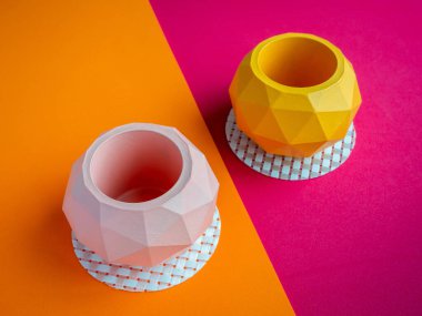 Kaktüs tenceresi. Beton çömlek. Renkli arka planda boş pembe ve turuncu modern geometrik beton ekiciler, üst görünüm.
