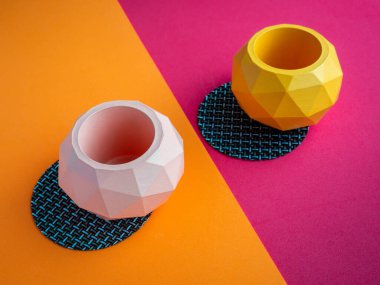 Kaktüs tenceresi. Beton çömlek. Renkli arka planda boş pembe ve turuncu modern geometrik beton ekiciler, üst görünüm.