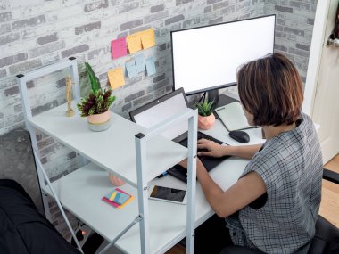Güzel mutlu Asyalı kadın laptopuyla çalışıyor yatak odasında beyaz ekranlı, apartman dairesinde. Ev konseptinde çalış.