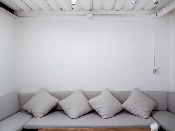 Minimalist style living room with grey sofa with throw pillows on white wall background with copy space.