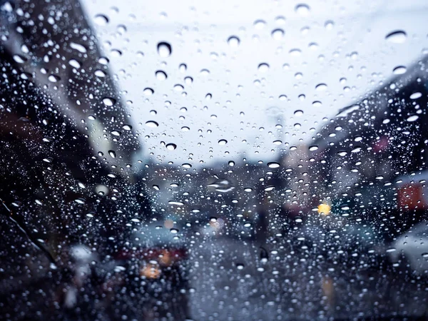 Water drops on windshield with blur street view in rainy day, view from inside the car. Street view in rainy day in rainy season.