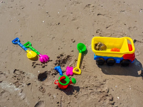儿童海滩玩具五彩缤纷 配有铲子 卡车和淋浴间 沙滩上的背景是湿沙滩 — 图库照片