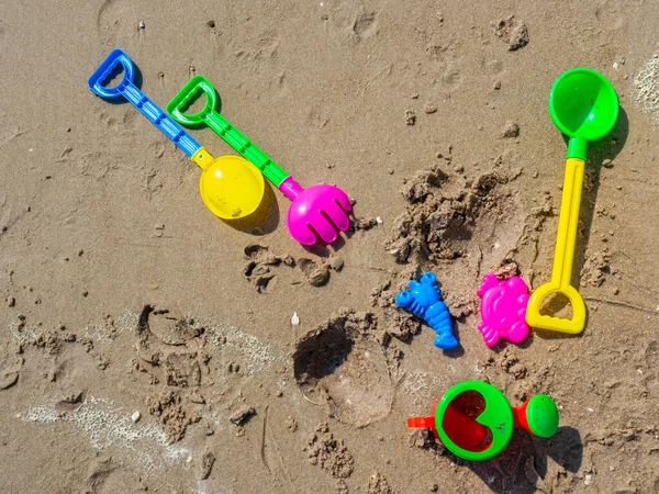 カラフルな子供のビーチのおもちゃ ビーチの背景にある湿った砂の上にシャベルとシャワーマグカップ付きの緑 — ストック写真