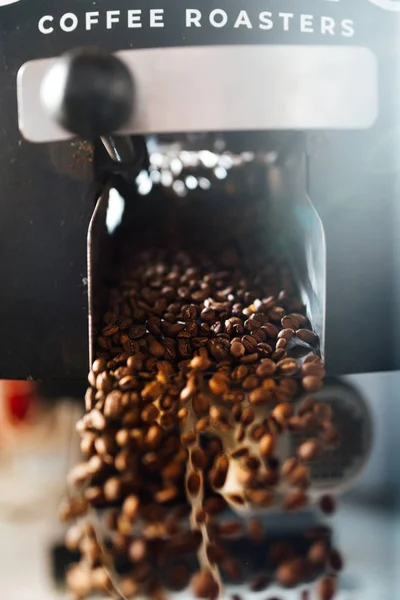 The flow of coffee beans from open flap of the cooling mixer of