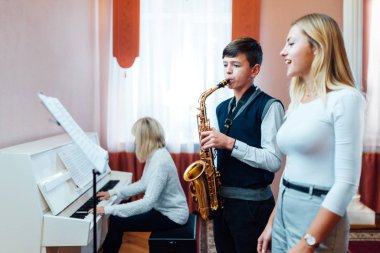 Erkek öğrenci saksafon çalmayı ac 'e müzik dersinde öğreniyor.