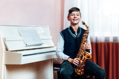 Neşeli öğrenci müzik dersinden önce saksafonla oturuyor.