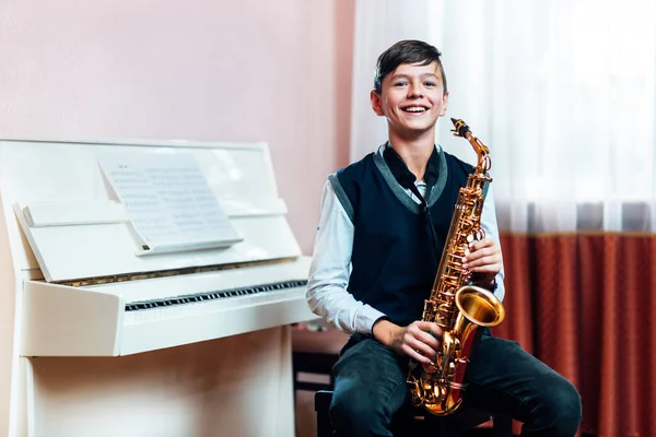 Allegro studente ragazzo seduto con sassofono prima lezione di musica — Foto Stock