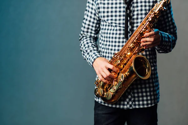 Sassofono in primo piano sulle mani su sfondo blu uniforme — Foto Stock