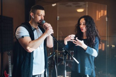 Müzik öğretmeni, genç bir erkek vokaliste koçluk yapıyor.