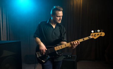 Sahnede elektro gitarist çalan bir erkek gitarist sahne arkası ışıklandırması ile taklit alanı olan bir mavi nokta ışığı altında canlı performans sırasında