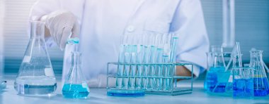 Bilim adamının elinde deney tüpleri, bilim ve tıbbi araştırma ve geliştirme konseptine kimyasal sıvı damlatan matara.