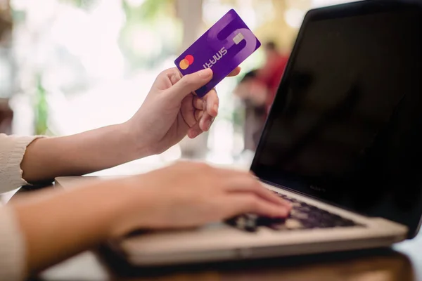 Kredi kartı tutan ve dizüstü bilgisayar kullanarak el. Online alışveriş kavramı