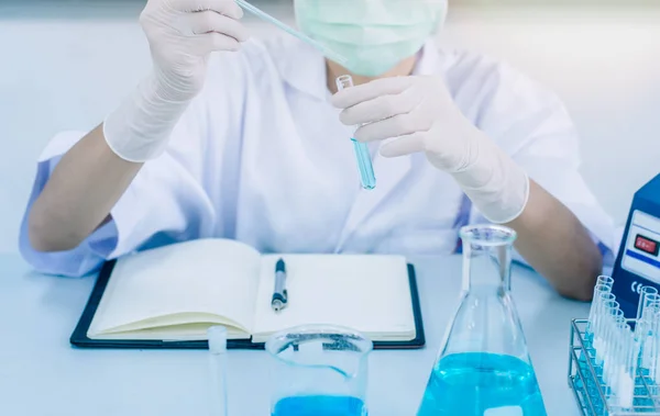 Kadın bilim adamı ya da doktor ile yeşil çözüm içinde laboratuvar - stok fotoğraf A kadın doktor ya da bir test tüpünde bir laboratuvar yeşil bir çözümün bakarak adli tıp.