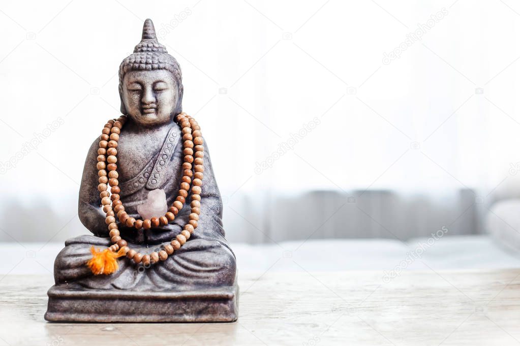 Buddha statue with beads. Buddha statue in bright room.