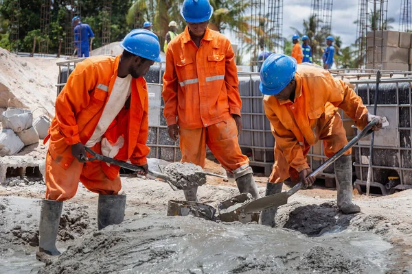 Byggnadsarbetare som skyfflar cement. — Stockfoto