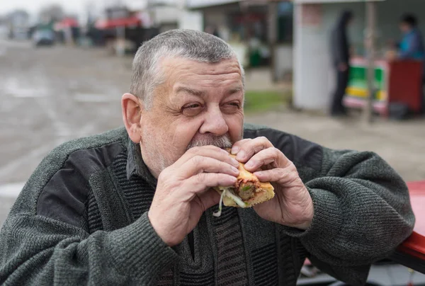 Portrait of Caucasian senior driver eating lyulya kebab in lavash