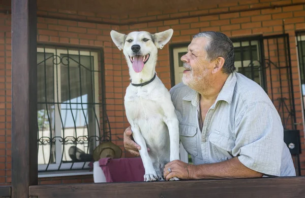 户外肖像的快乐混合品种白狗与其欢快的胡子资深大师摆在他们的房子附近 — 图库照片