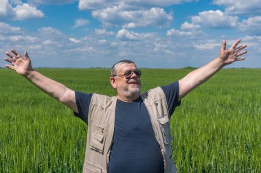 Gülümseyen kıdemli çiftçi olgunlaşmamış bitkileri alan forma kollu içinde daimi portresi