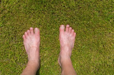 Kesme çim üzerinde duran adamın feets olgun. Yukarıdan ateş.