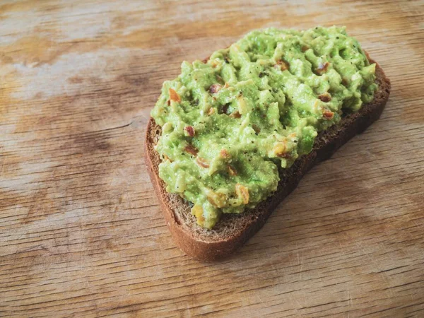 Sanduíche simples com guacamole deitado em uma superfície de madeira — Fotografia de Stock