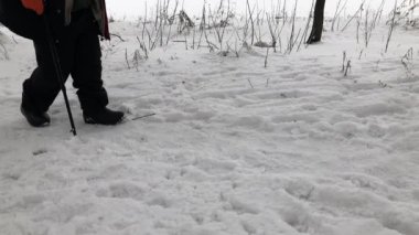 Karla kaplı bir yolda bastonuyla ağır ağır yürüyen yaşlı adam.