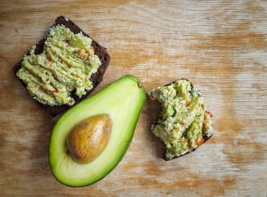 Avokado yarısı ve guacamole soslu iki sandviç.