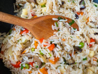 Sebzelerle pişirilmiş beyaz pirince saplanmış ahşap kaşık manzarası..