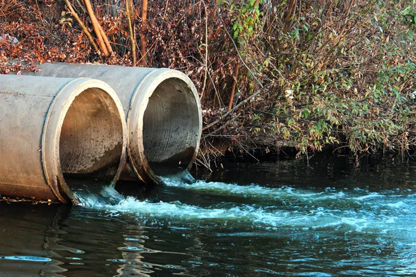 Descarga de esgoto em um rio — Fotografia de Stock