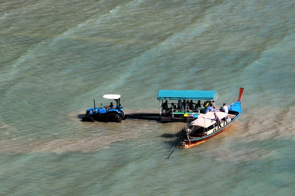 Los turistas usan tractores y remolques para llegar al bote de cola larga durante la marea baja en Railay West Bay, un popular resort en Krabi, Tailandia — Foto de Stock