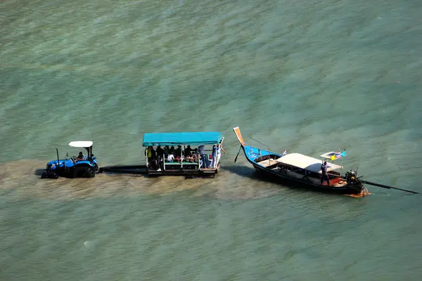 Los turistas usan tractores y remolques para llegar al bote de cola larga durante la marea baja en Railay West Bay, un popular resort en Krabi, Tailandia — Foto de Stock