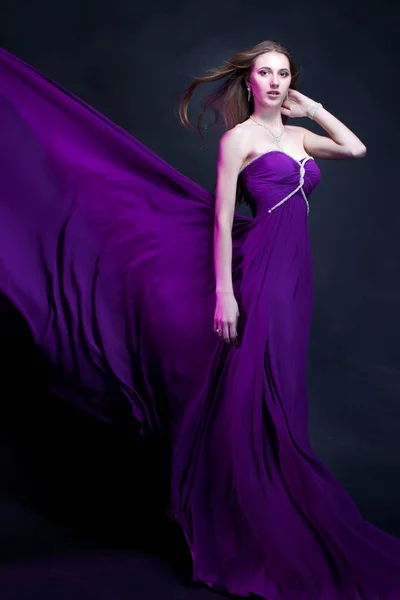 Donna di moda in abito viola con trucco magico e acconciatura Foto Stock