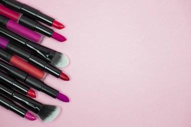 Makyaj seti, rujlar, pembe arka planda dudak parlatıcıları. Üst Manzara. kopyalama alanı. yatay