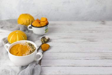 Beyaz bir tabakta balkabağı kremalı çorba. Klasik mavi arka planda. Küçük dekoratif balkabakları, mavi gazlı bez ve bir kaşıkla. Boşluğu kopyala