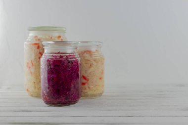 Üç cam kavanoz mayalanmış beyaz, kırmızı lahana. Hafif arka planda sebzeler. fermantasyon bir probiyotik kaynağıdır. Boşluğu kopyala