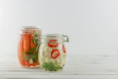 İki cam kavanoz mayalanmış karnabahar ve havuç. Hafif arka planda sebzeler. fermantasyon bir probiyotik kaynağıdır