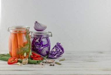 iki cam kavanoz mayalanmış kırmızı lahana, soğan, havuç. Hafif arka planda sebzeler. Tekstil yeşili kullanıyor. fermantasyon bir probiyotik kaynağıdır. Popüler vejetaryen yemekleri. Boşluğu kopyala