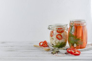 İki cam kavanoz mayalanmış karnabahar ve havuç. Hafif arka planda sebzeler. Tekstil açık gri kullanıyor. fermantasyon bir probiyotik kaynağıdır. Boşluğu kopyala