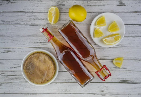 Комбуча суперпища про биотик чай грибок напиток в стеклянной бутылке с лимоном на белом деревянном фоне — стоковое фото