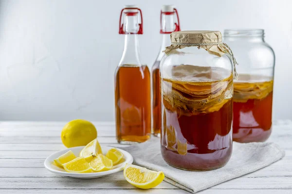 Kombucha süper yiyeceği, beyaz arka planda limonlu cam şişe ve kavanozda biyotik çay mantarı içeceği. Boşluğu kopyala