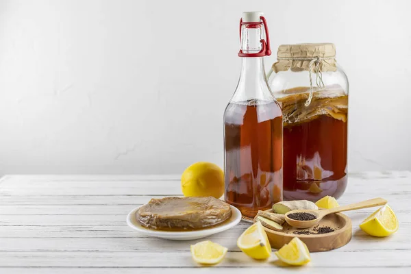 Kombu çin süper yiyeceği biyotik çay mantarı, cam şişe ve limon, zencefil ve beyaz arka planda çay dolu kavanoz. Boşluğu kopyala