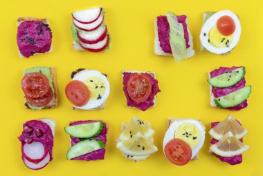 Pancar humusu, guacamole ve farklı sebzelerle farklı bruschetta sandviçleri hazırla. Vejetaryen Helsifood konsepti. Yaz atıştırması. Sarı arka planda yiyecek örnekleri