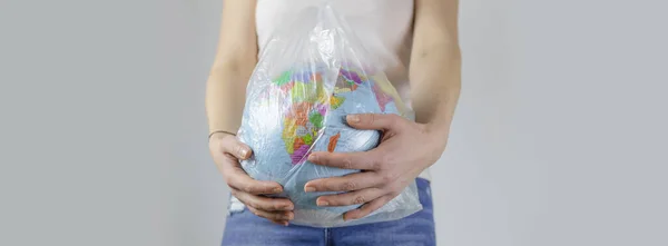 girl holds an earth globe in a plastic bag. plastic free concept, eco friendly, zero waste lifestyle, conscious resource consumption. planet ecology. banner