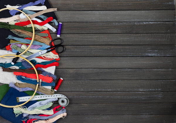 there are quilting, embroidery and sewing tools on the table. patchwork knife, scissors, lined cutting mat, self-locking, threads, measuring tape, floss, hoop. copy space