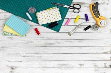 Masanın üzerinde örtü, nakış ve dikiş aletleri var. Yama bıçağı, makas, hasırlı kesim paspası, kendini kilitleme, iplikler, mezura, diş ipi, halka. Boşluğu kopyala