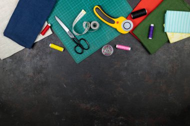 Masanın üzerinde örtü, nakış ve dikiş aletleri var. Yama bıçağı, makas, hasırlı kesim paspası, kendini kilitleme, iplikler, mezura, diş ipi, çember. Boşluğu kopyala