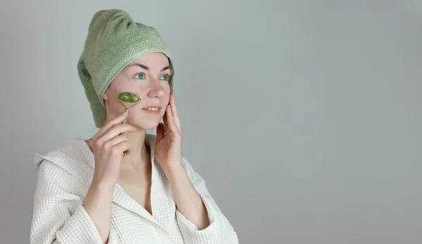 Kafasında havlu olan Avrupalı bir kadın yeşim taşıyla Guasha 'ya masaj yapıyor. Spa sağlık konsepti. Boşluğu kopyala