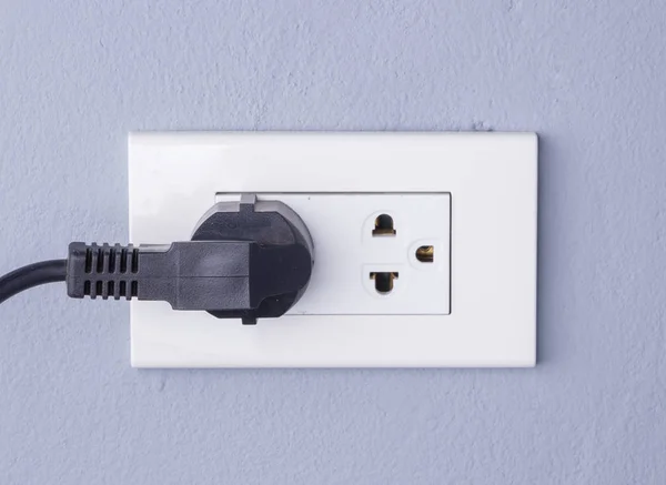 Cable negro enchufado en un enchufe eléctrico blanco montado en gris w —  Fotos de Stock