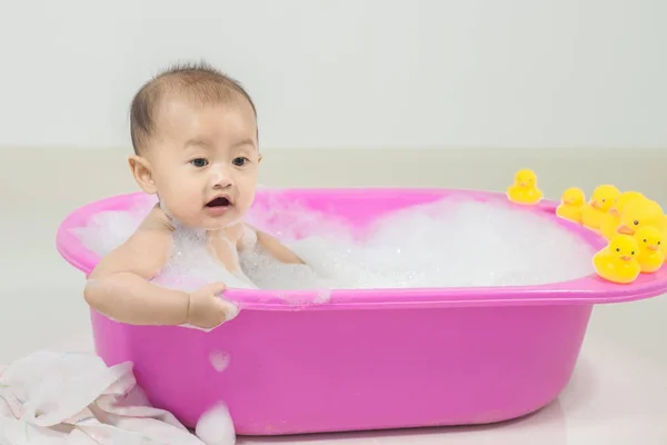 Ребенок принимает ванну в ванне и играет с пеной пузырьки — стоковое фото