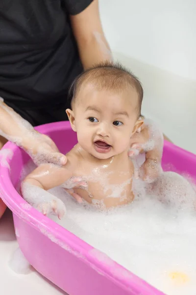 Bebé tomando un baño en la bañera y jugando con burbujas de espuma — Foto de Stock