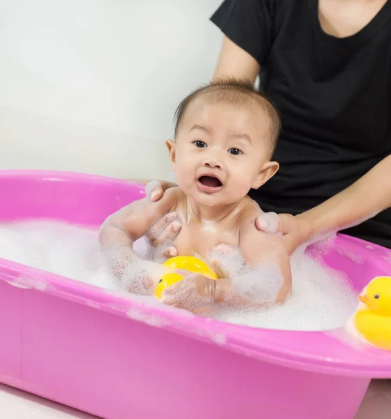 Bebé tomando un baño en la bañera y jugando con burbujas de espuma — Foto de Stock